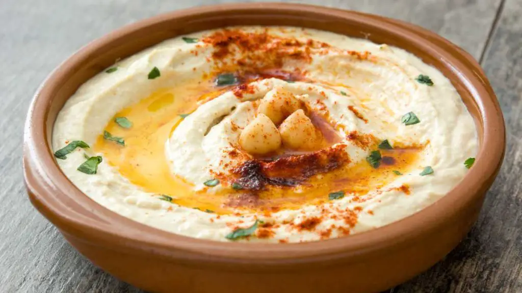 A picture of hummus served in a wooden plate - Does Hummus Need Refrigeration?